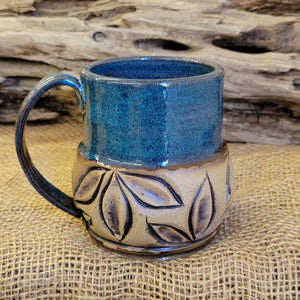 Mug is glazed with a deep indigo blue and iron wash applied on carved texture
