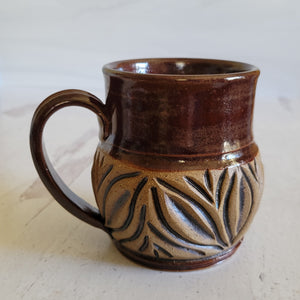 Carved mug is glazed with a deep red glaze