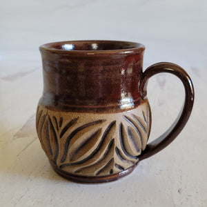 Carved mug is glazed with a deep red glaze