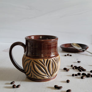 Carved mug is glazed with a deep red glaze