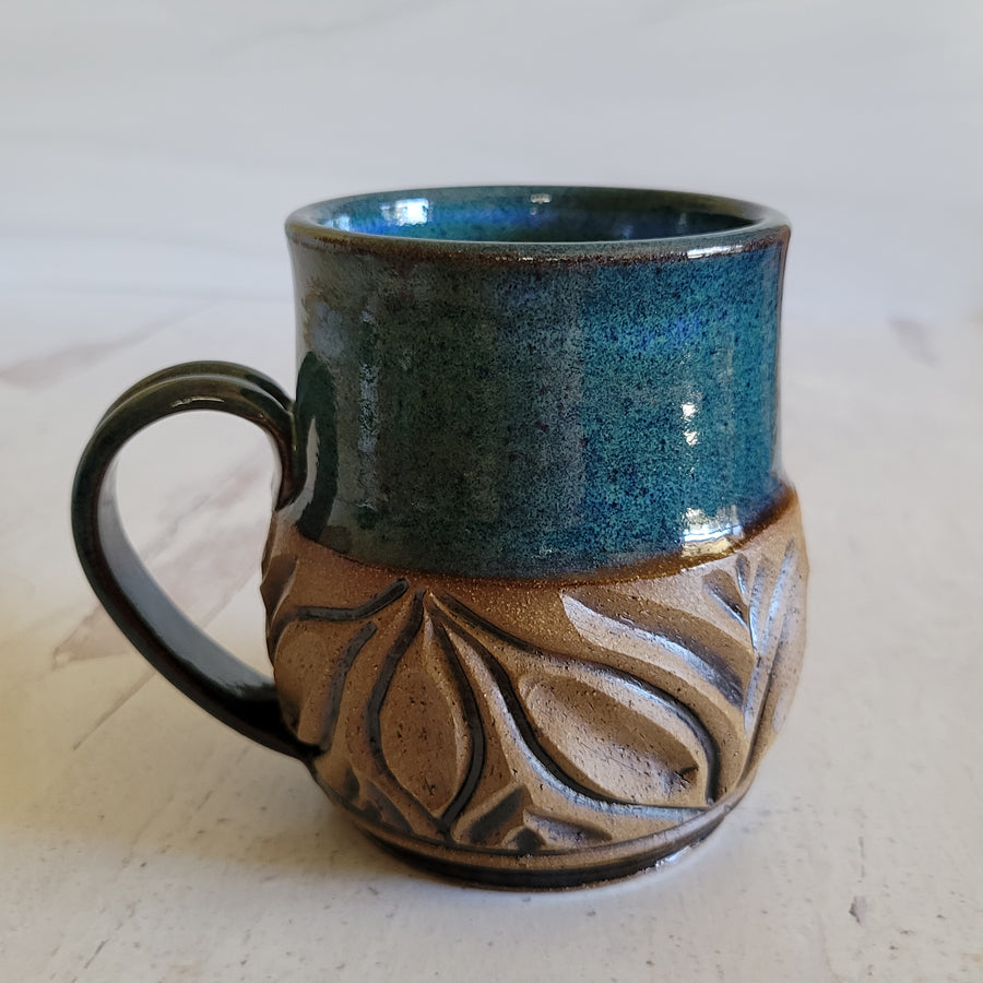 Carved mug is glazed with an indigo blue glaze.