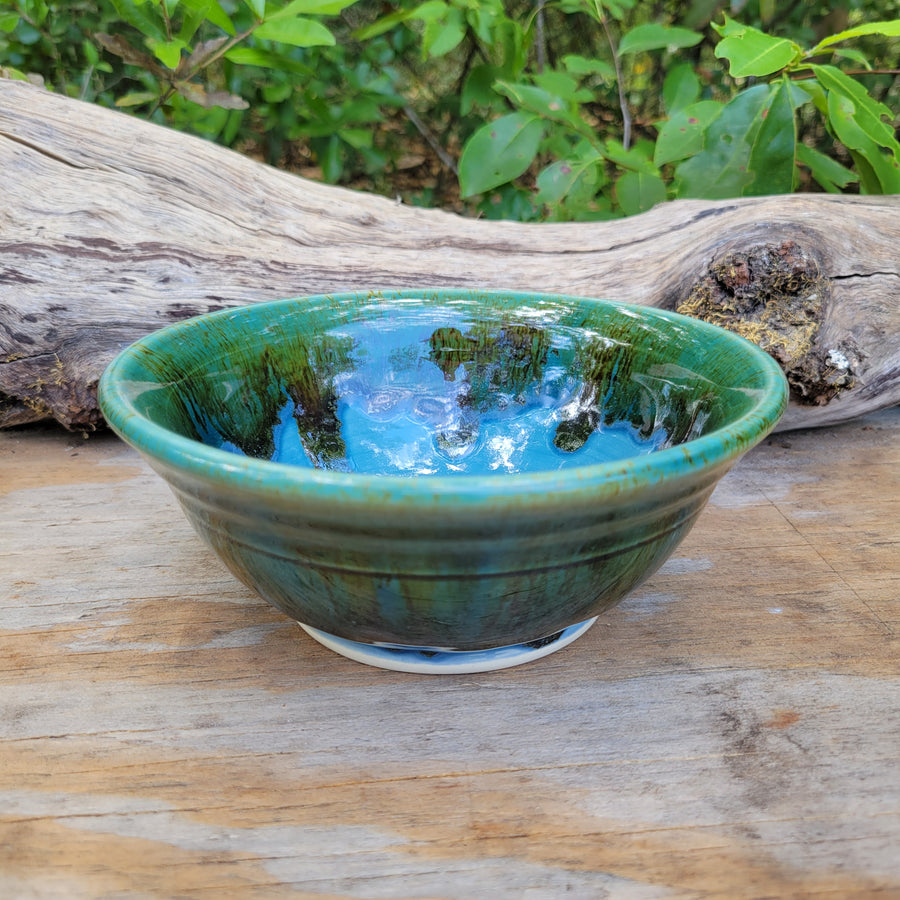 Wheel-thrown bowl with blue glazed interior and greenish brown accents on rim