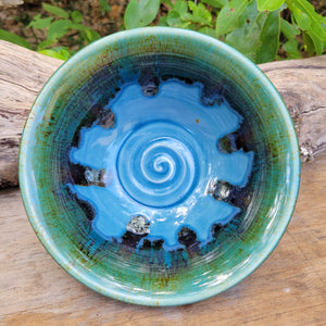 Wheel-thrown bowl with blue glazed interior and greenish brown accents on rim_overhead view