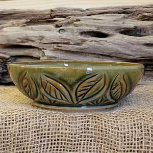 Wheel thrown bowl has a blue celadon glaze with additional blue-green accents