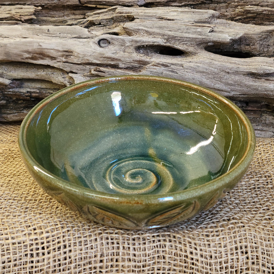 Wheel thrown bowl has a blue celadon glaze with additional blue-green accents