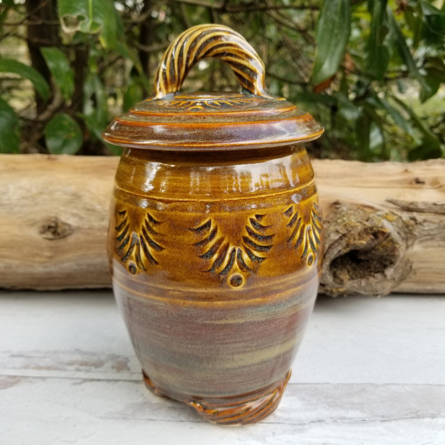 Carved lidded jar has gold-brown glaze with light cream/copper glaze accents