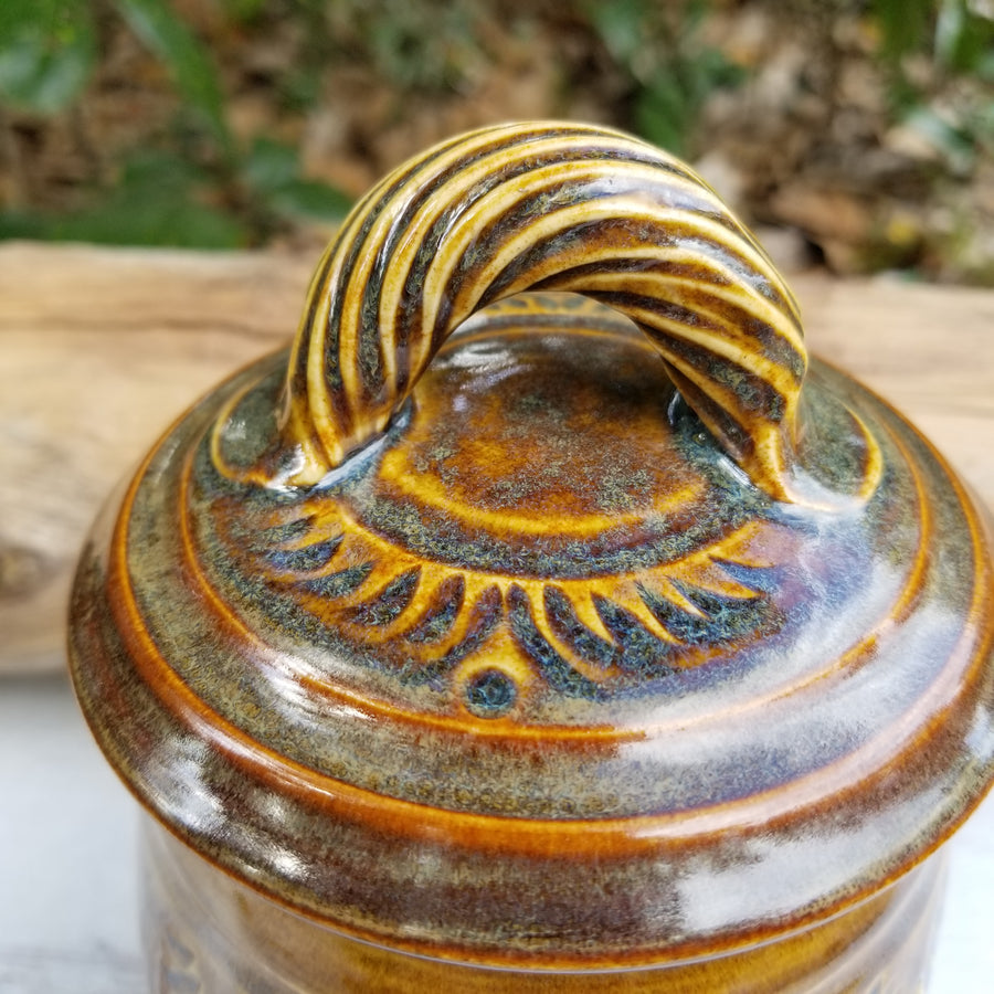Carved lidded jar has gold-brown glaze with light cream/copper glaze accents_lid view